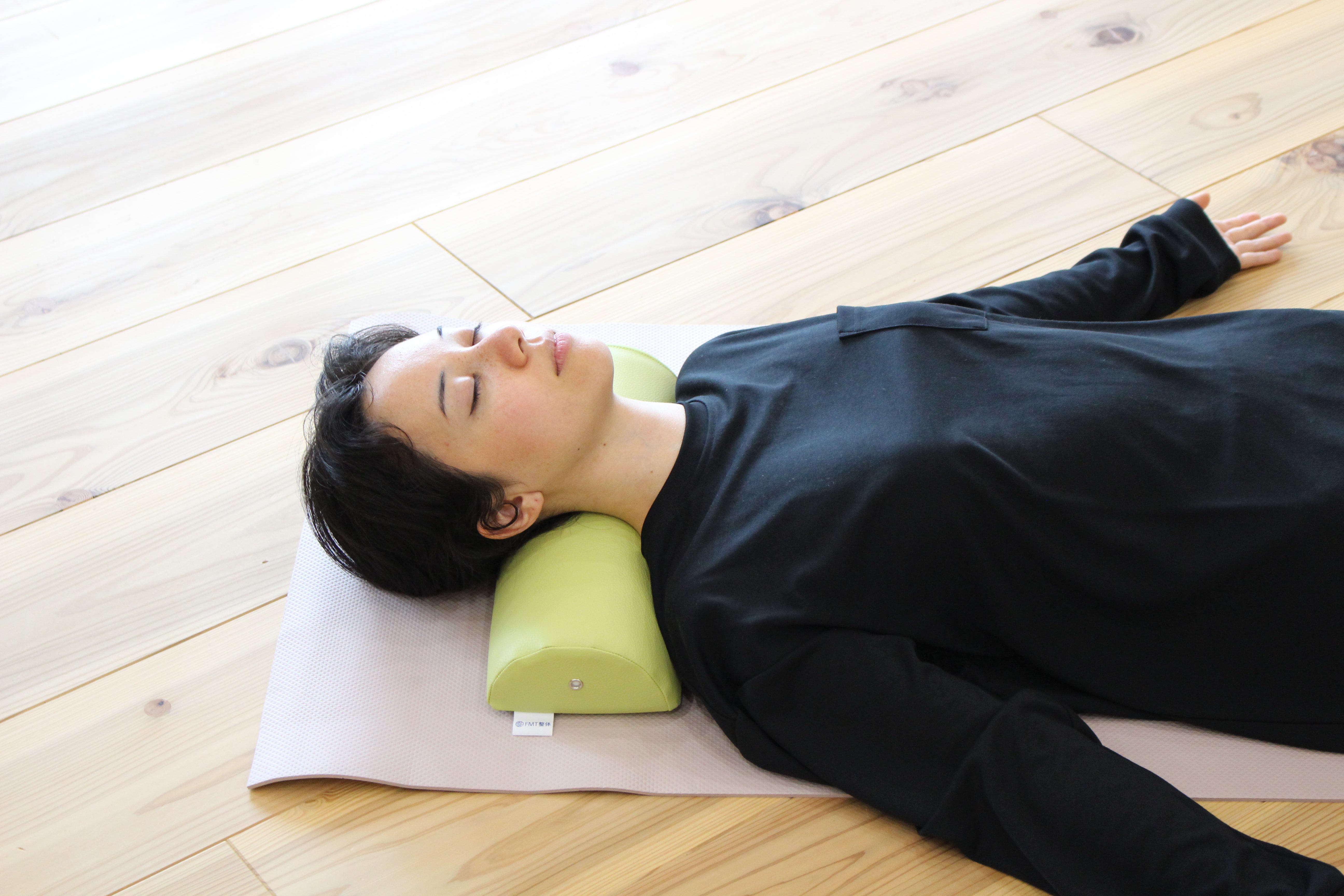 A woman demonstrates using the NeckEz Pillow to stretch her neck.