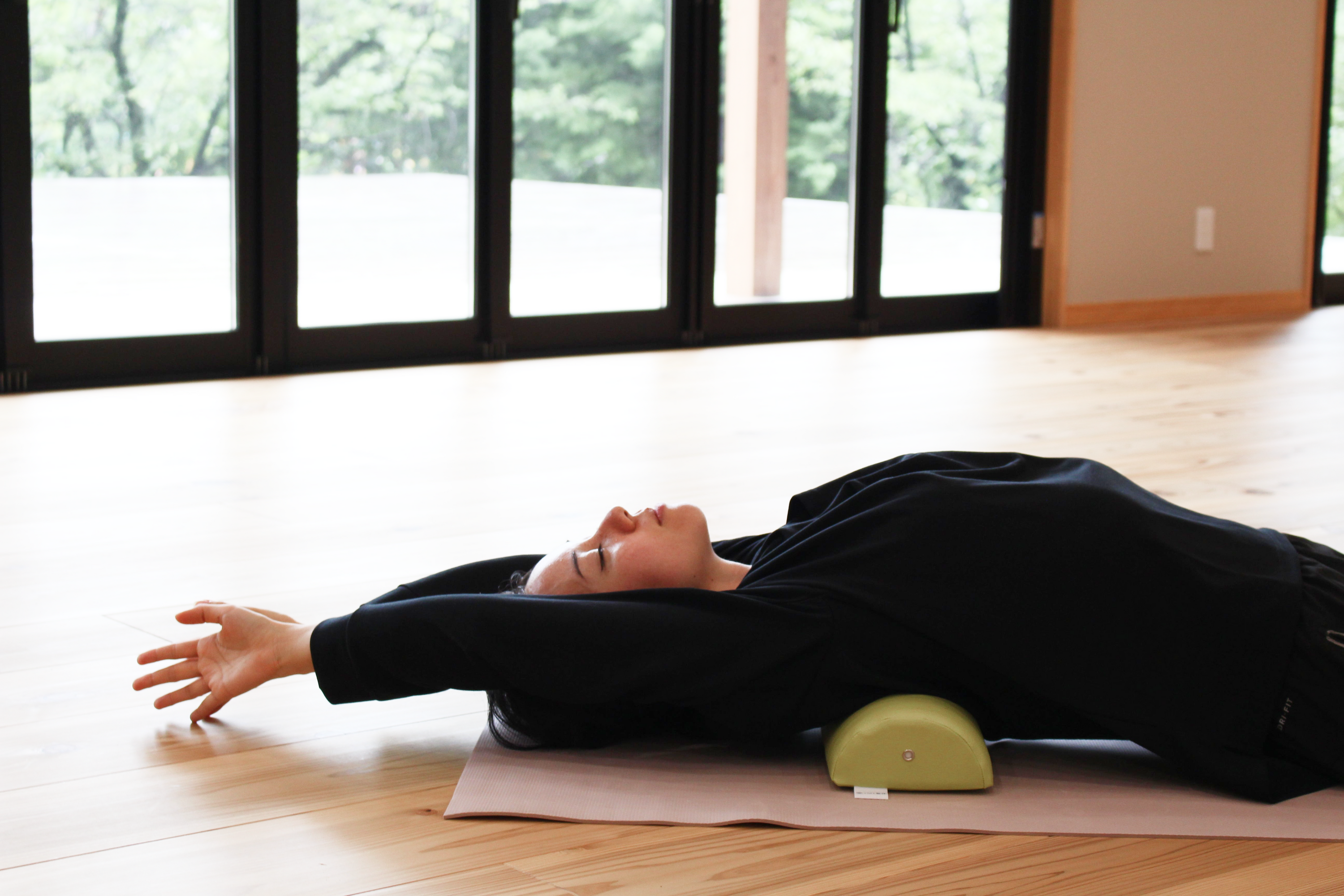 A woman demonstrates using the NeckEz Pillow to stretch her shoulders.