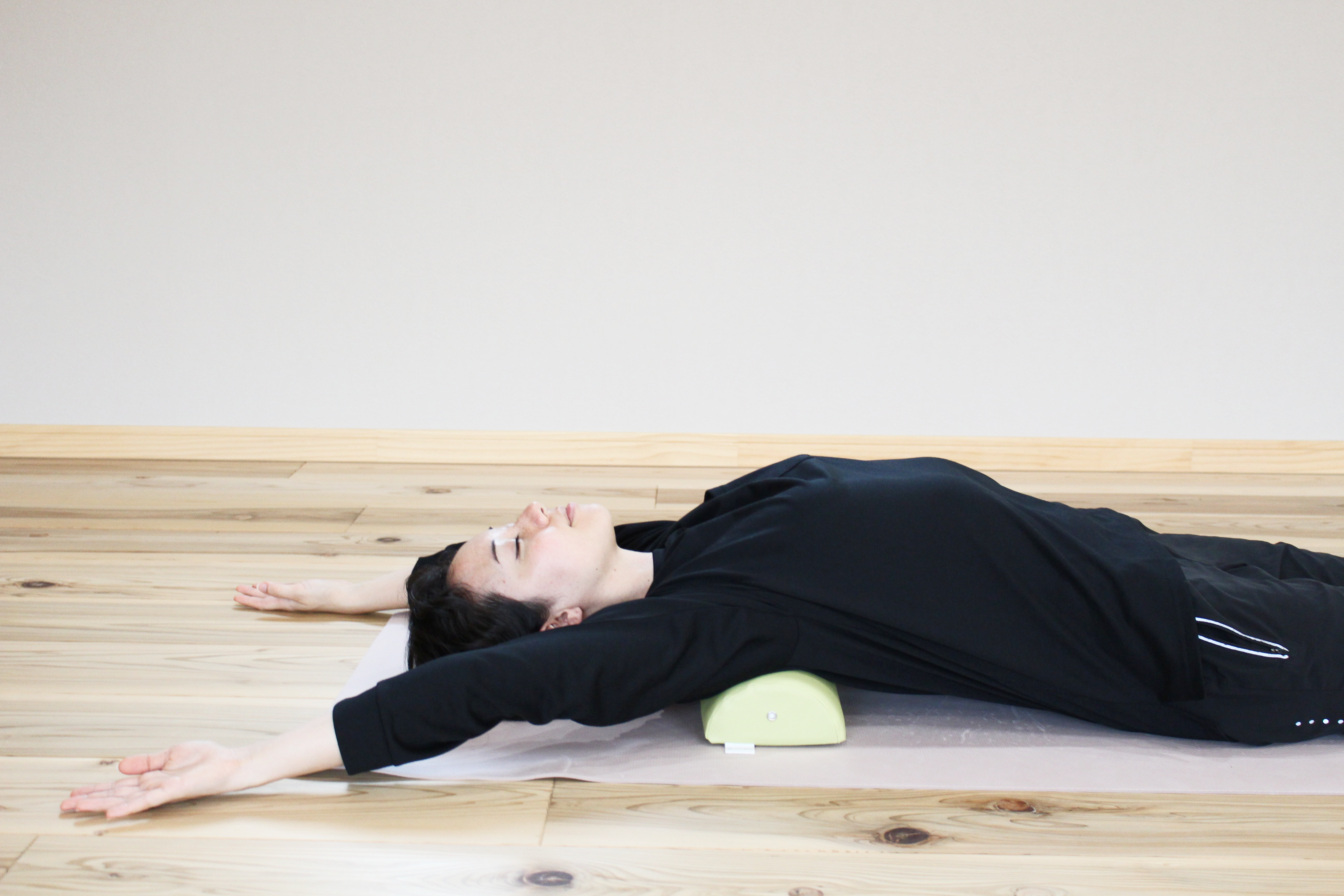 A woman demonstrates using the NeckEz Pillow to stretch her shoulders.